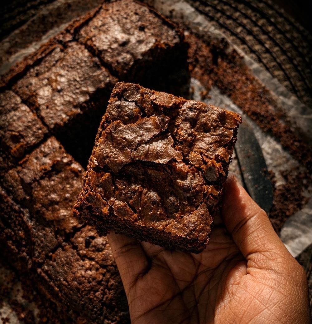 Freshly baked fudgy chocolate brownie held in hand